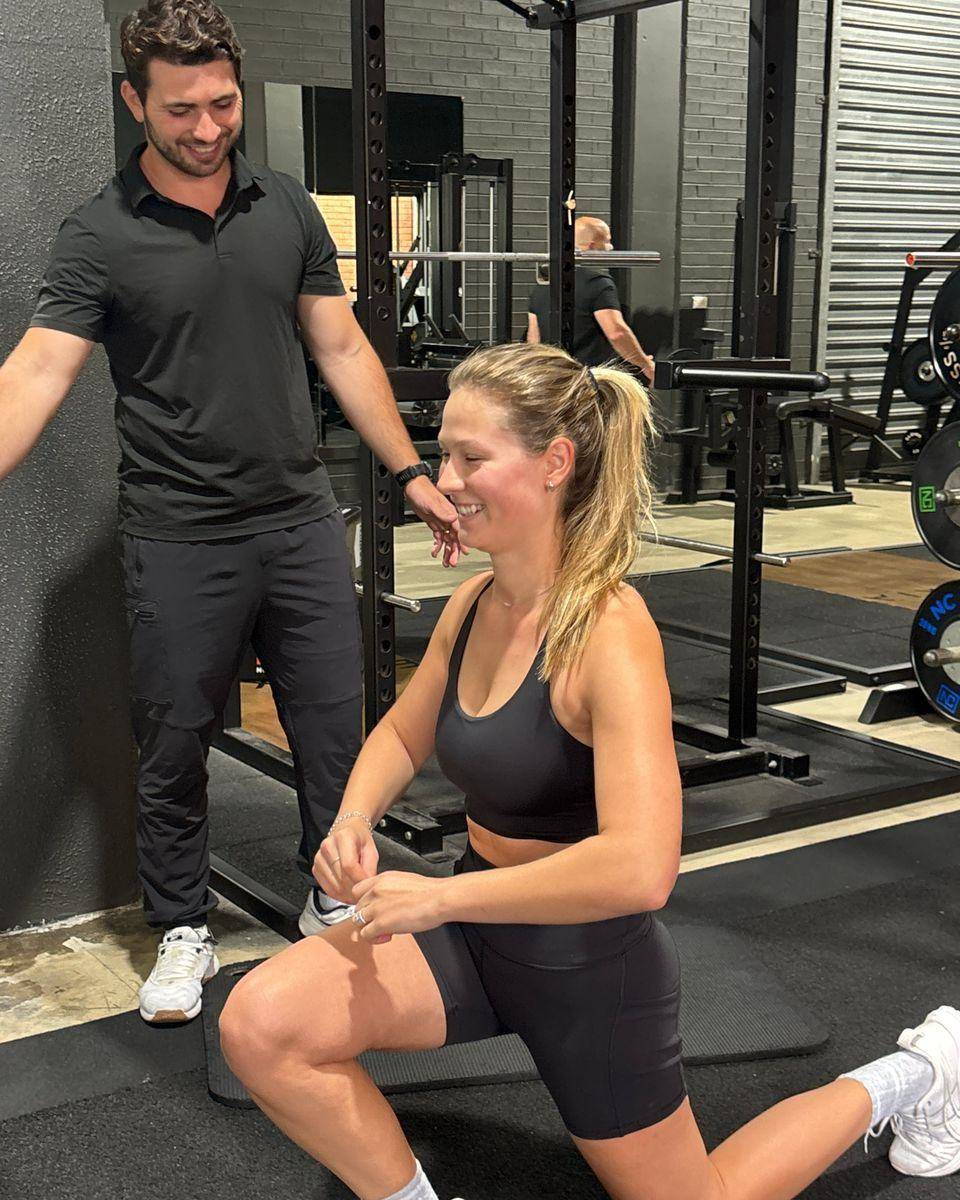 A client smiling mid-session as Max coaches her kneeling drill