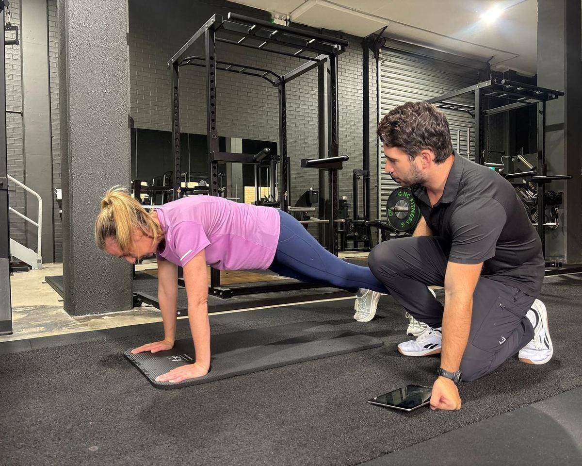 Personal Trainer Brookvale — Solve PT Max assessing a client’s plank and logging it on his iPad
