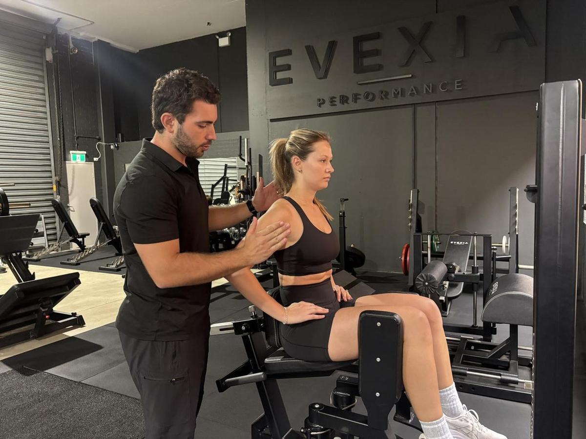Max adjusting a seated client’s shoulder position during a posture assessment