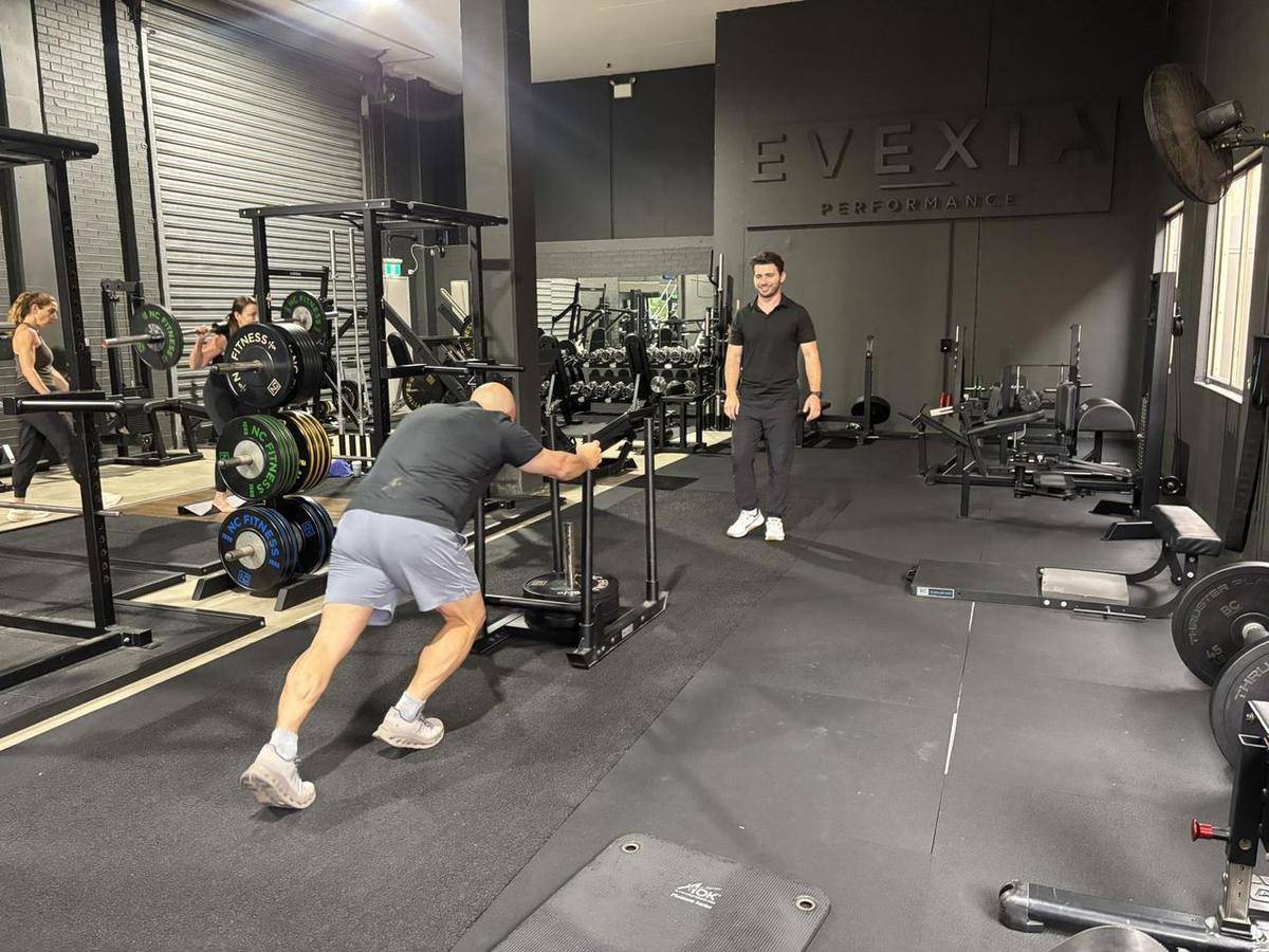 A client driving a loaded sled across the gym floor