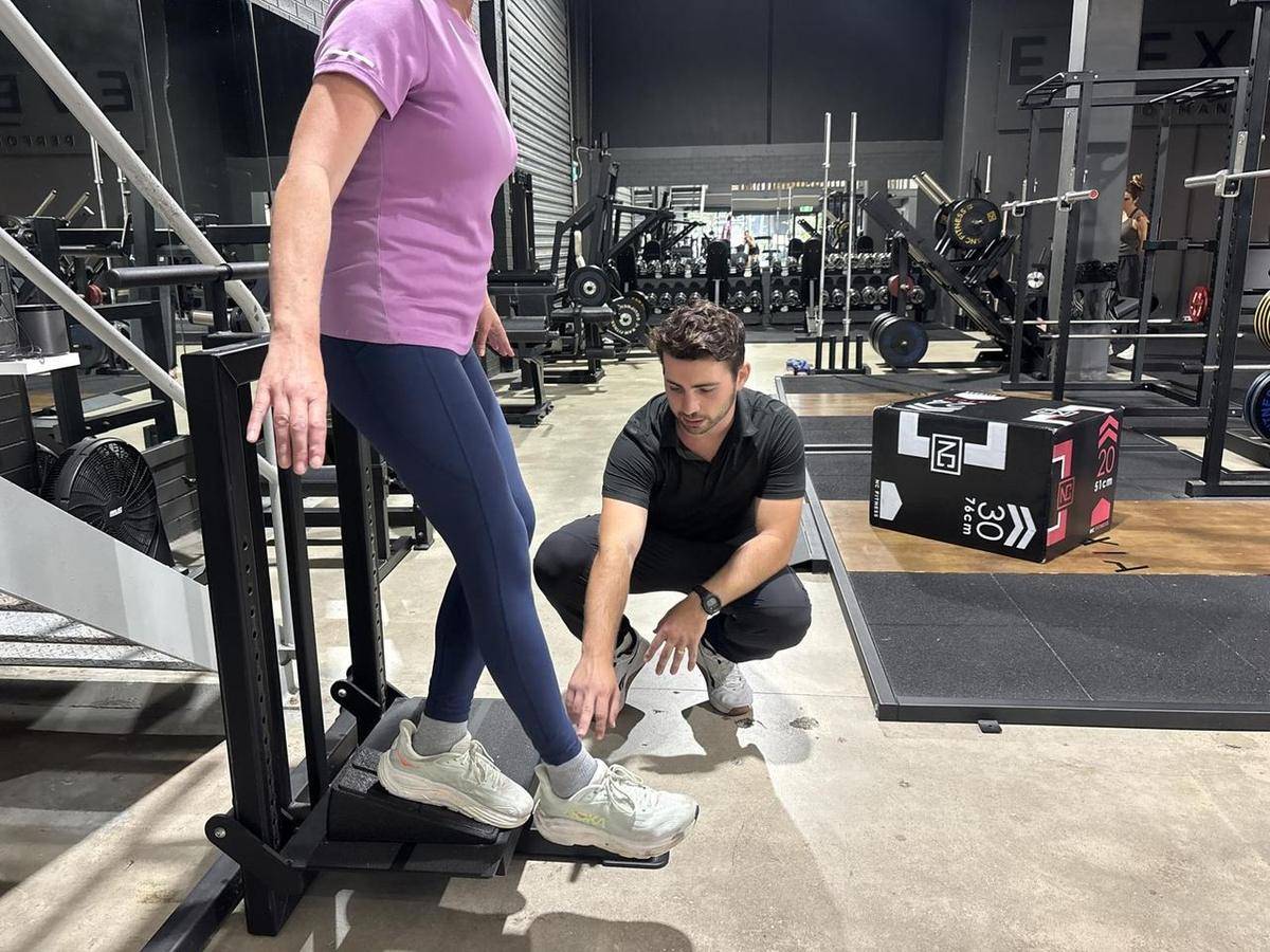 Max coaching a client through a box step-up, watching every rep